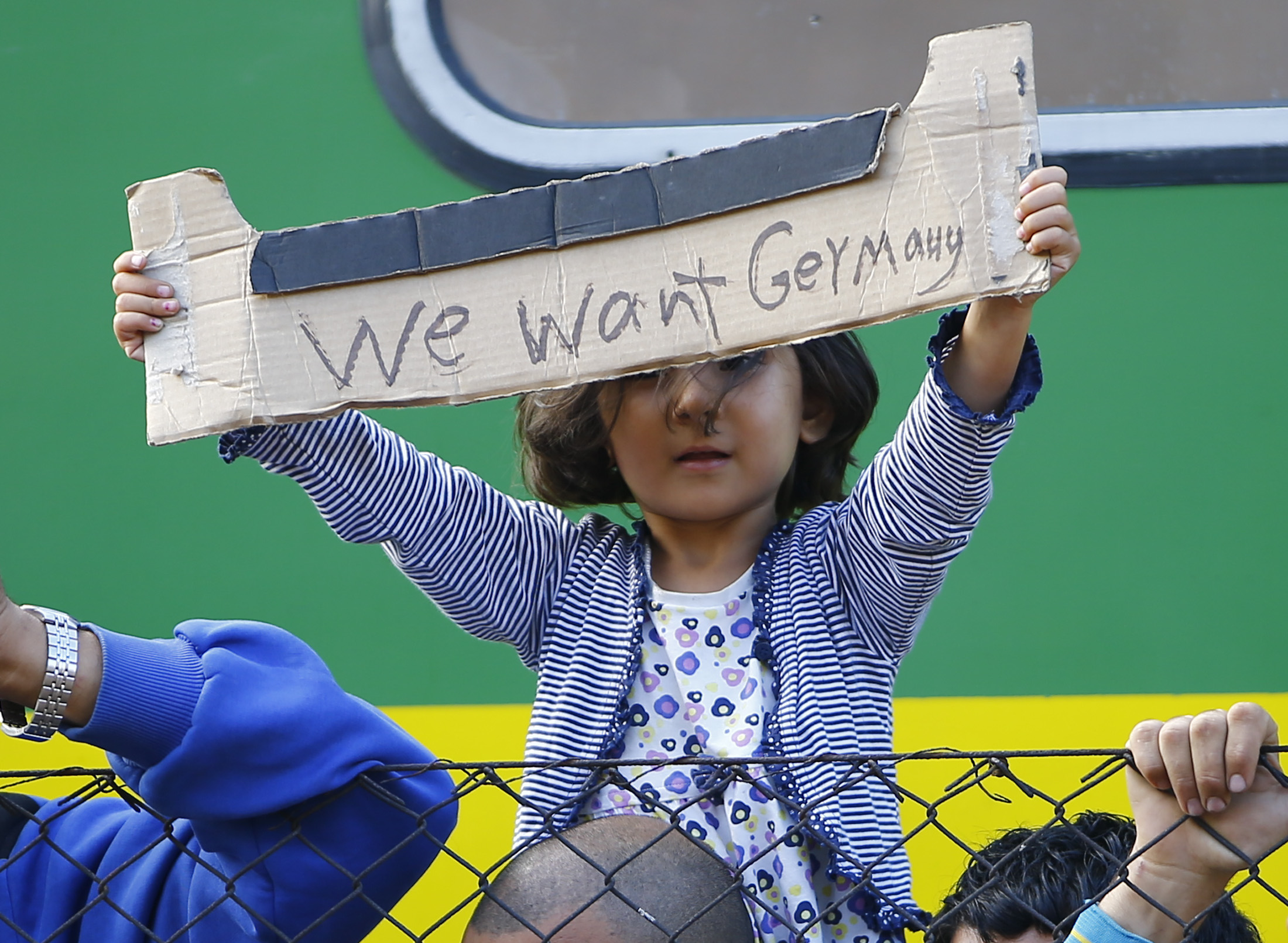 A young migrant girl holds up a sign during a protest in front of a train at Bicske railway station