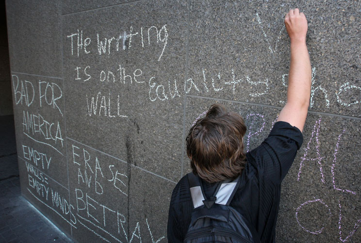 An Occupy LA protester uses chalk to write on a Bank of America during the Move Your Money March on what is being called Bank Transfer Day on November 5, 2011 in Los Angeles, California.