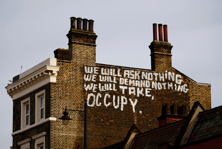 Graffiti on the side of a building in Bishopsgate in support of the Occupy London movement displays the message 'we will ask nothing we will demand nothing we will take, occupy.' near the City on November 23, 2011 in London, England.